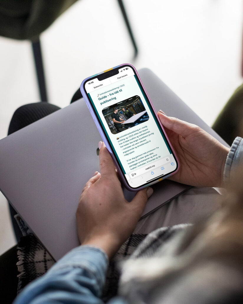 En person sitter på en stol med mobiltelefonen i hånden, og leser et nyhetsbrev.